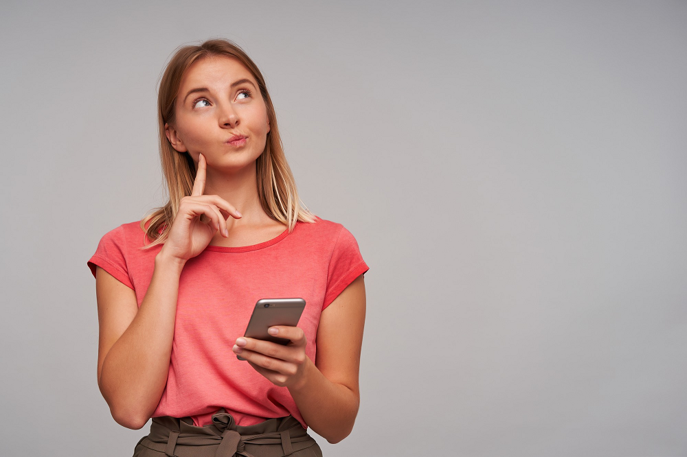 Mujer con celular tiene expresión de interrogación