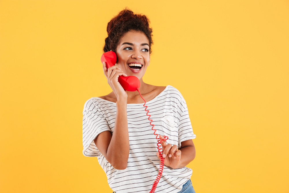 Mujer habla por teléfono con un teléfono rojo fijo