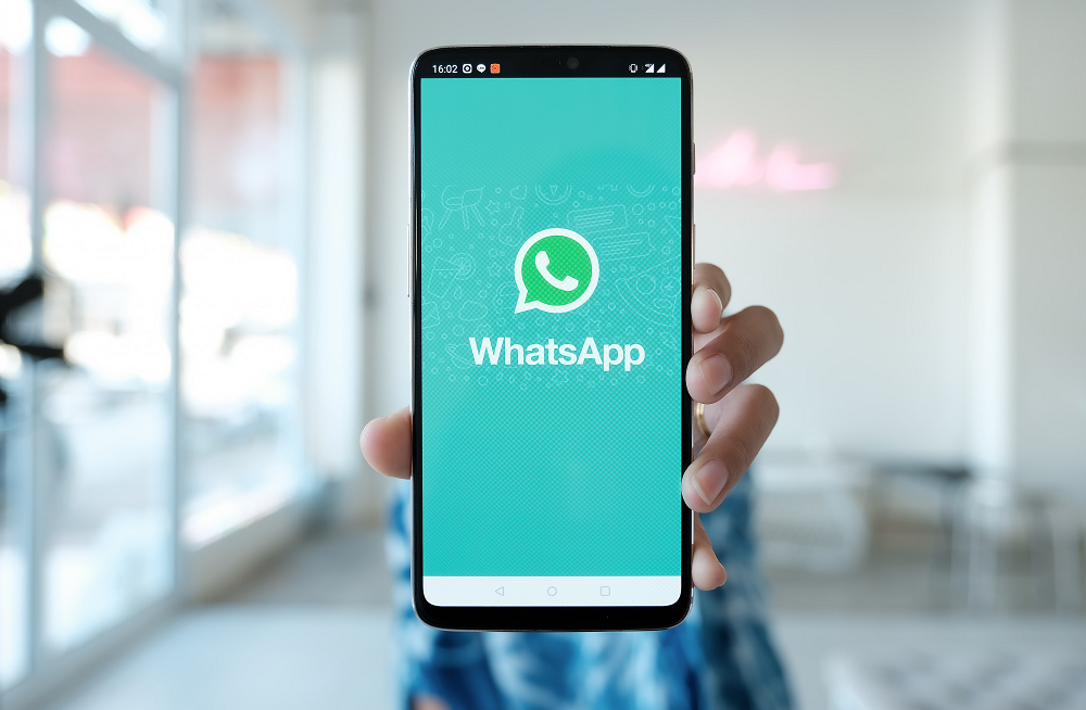 wa.me: persona sostiene teléfono celular con el logo de whatsapp en la pantalla