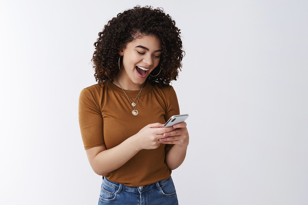 Mujer joven revisa sonriente su celular