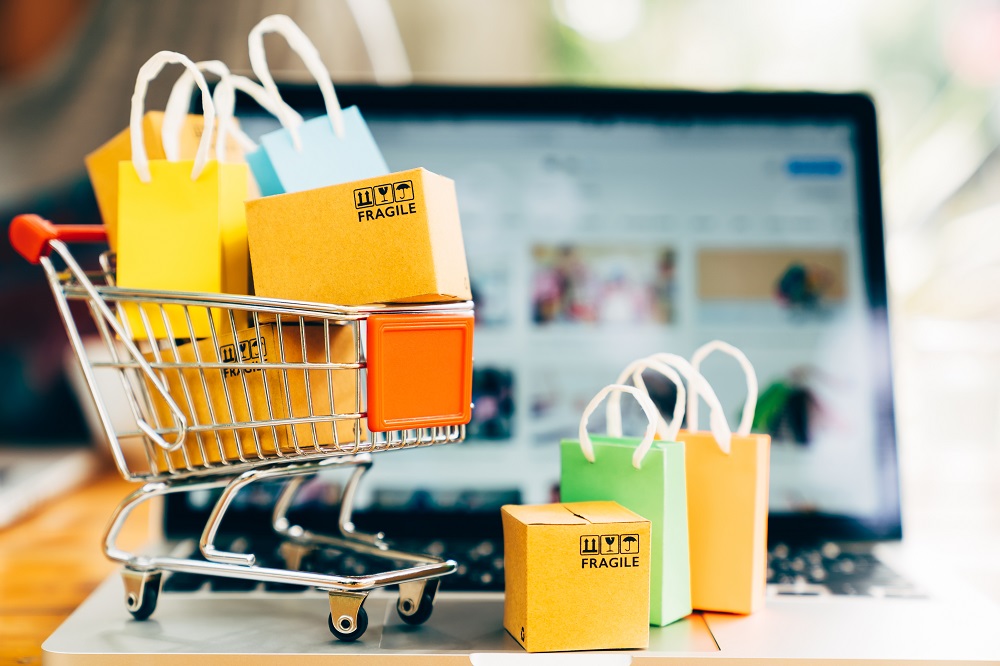 Composición sobre compras online: computadora y carrito de compra